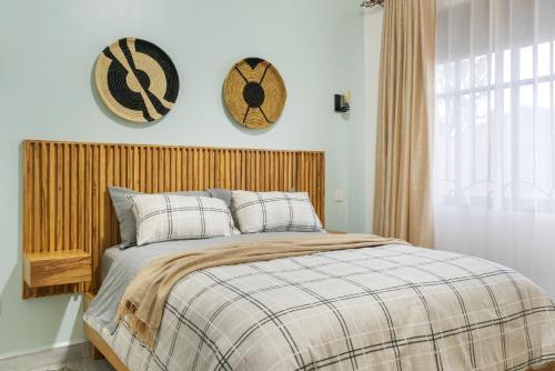 a bedroom with a bed with two hats on the wall at Polo Apartments in Kampala