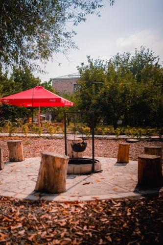 a table with a red umbrella and some trees at Village Jazz in Chimankend