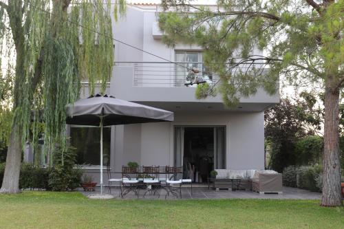 a white house with a table and an umbrella at Virna s home in Schinias