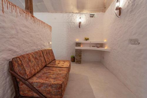 a couch sitting in a room with a wall at Deshadan Eco Valley Resort - An Eco friendly Mud House in Kanthalloor