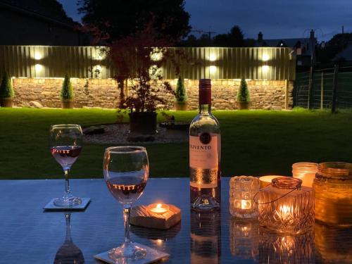 Una botella de vino y dos copas en una mesa. en Courtyard Cottage en Lockerbie