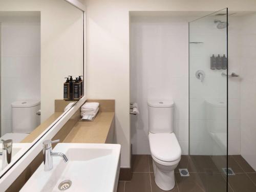 a bathroom with a toilet and a sink and a shower at Mercure Sydney Parramatta in Sydney