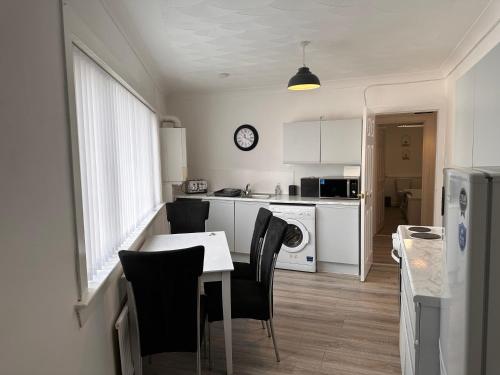 a kitchen with a table and chairs and a kitchen with a clock at Crown street getaway in Ayr