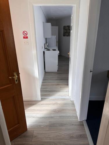 a hallway leading to a room with white walls and wood floors at No 19 Serviced Apartment in Ayr