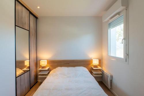 une chambre avec un grand lit et deux lumières sur les tables dans l'établissement Ravissante maison 3* avec jacuzzi proche lac, à Biscarrosse