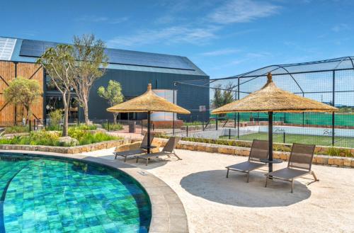 a swimming pool with chairs and umbrellas at Taina Apartment @ Green Creek in Pretoria