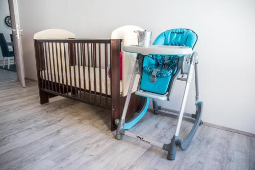 - une chaise haute bleue à côté d'un lit bébé dans l'établissement L&L Luxury Apartments, à Bitola