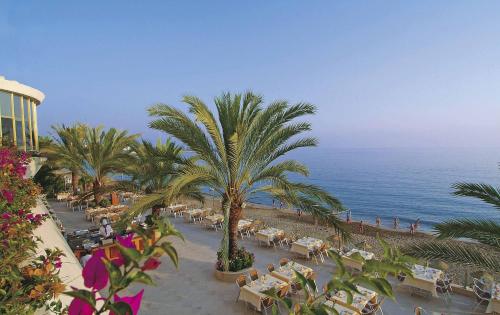 a beach with tables and palm trees and the ocean at Rubi Hotel in Avsallar