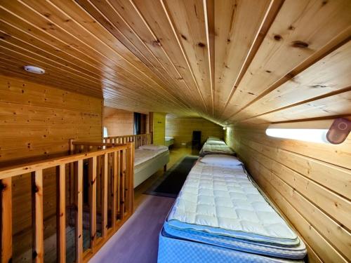 Habitación con 2 camas en una habitación de madera en Himos Virpi 8 hlö mökki porealtaalla, ei lisäkuluja!, en Jämsä