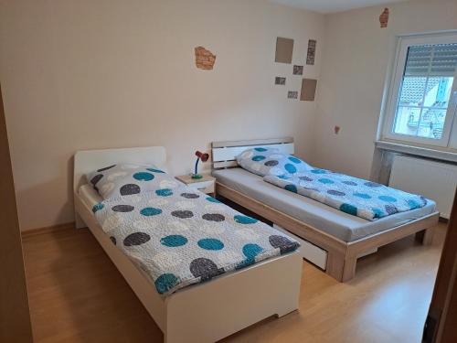 2 Betten in einem kleinen Zimmer mit Fenster in der Unterkunft Ferienwohnung Schleiten in Püttlingen