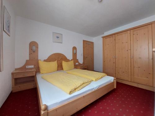 レンゲンフェルトにあるHaus Tanjaのベッドルーム1室(黄色いシーツと木製キャビネット付きのベッド1台付)