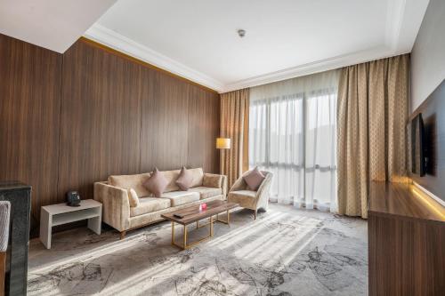 a living room with a couch and a tv at Grand Millennium Al Seef Basra in Al Başrah