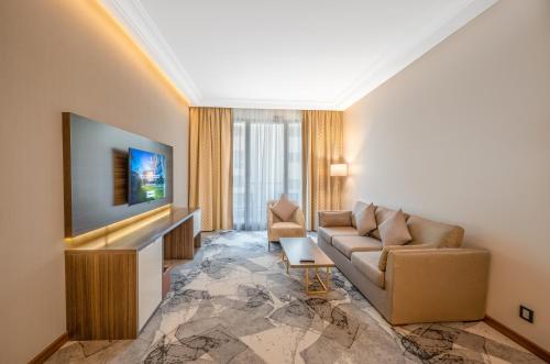 a living room with a couch and a tv at Grand Millennium Al Seef Basra in Al Başrah