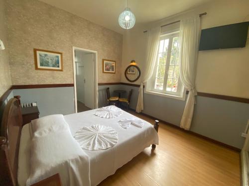 1 dormitorio con cama blanca y ventana en Pousada Villa, en Campos do Jordão