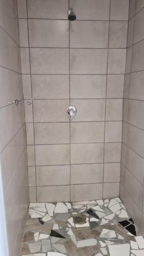 a bathroom with a shower with a tiled floor at The Unit Party House in eNyalungu