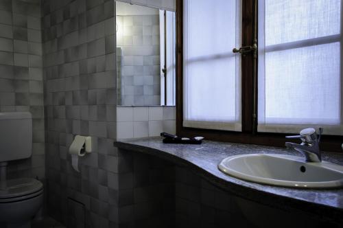 a bathroom with a sink and a window and a toilet at Locanda Piemonte da Sciolla in Domodossola