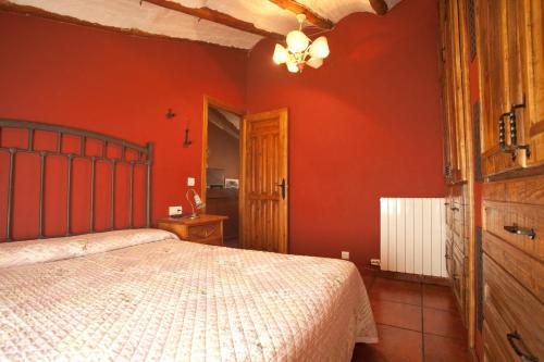 a bedroom with red walls and a bed in it at El Rincón de Bezas in Bezas