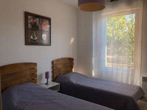 deux lits dans une chambre avec une fenêtre dans l'établissement LénaLac - résidence 3 étoiles - Aureilhan bord du lac, à Aureilhan