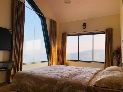 a bedroom with a bed and a large window at Rozaan Villa Valley View in Mahabaleshwar