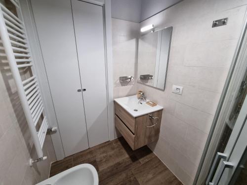 Baño blanco con lavabo y espejo en Moda Apartments 38, en Sestriere
