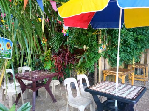 a patio with tables and chairs and an umbrella at Aquing's Place in El Nido