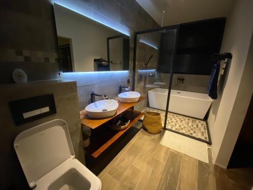 łazienka z 2 umywalkami, toaletą i wanną w obiekcie Green Creek Villa w mieście Flic-en-Flac