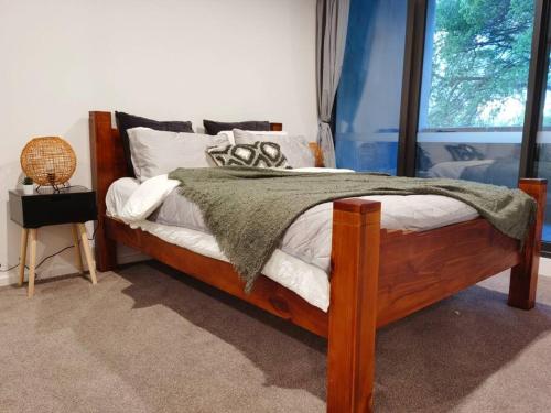 a bedroom with a wooden bed and a window at Brand New Luxe SOL Canberra CBD One bedroom Apartment in Canberra