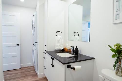 a white bathroom with a sink and a mirror at Le 908, suberbe condo neuf avec piscine in Quebec City