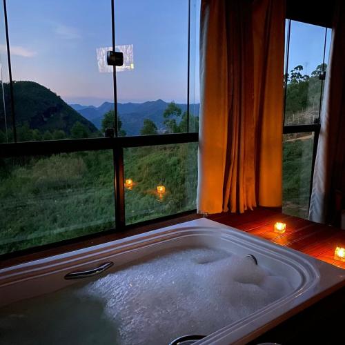 a bath tub in front of a window with a view at Vila Italliana Chalés - Chalé Milão in Santa Teresa