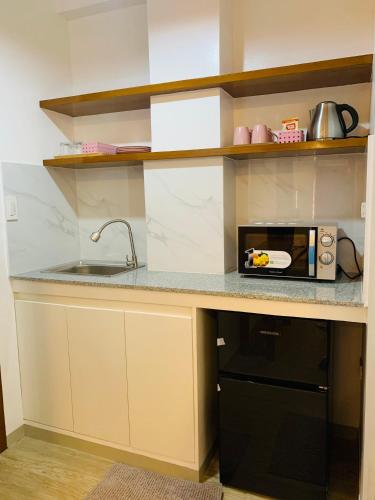 a kitchen counter with a microwave and a sink at Cozy Unit at the heart of Balanga City in Balanga