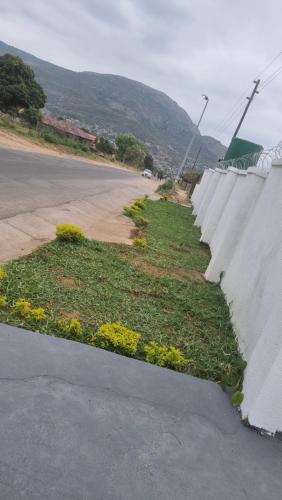 een betonnen muur met bloemen aan de kant van een weg bij The Unit Party House in eNyalungu