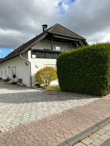 ein weißes Haus mit einer Hecke davor in der Unterkunft Kleine Auszeit in Goslar