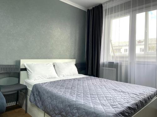 a bedroom with a bed and a window and a chair at Квартира целиком в центре 4 спальных места in Petropavlovsk