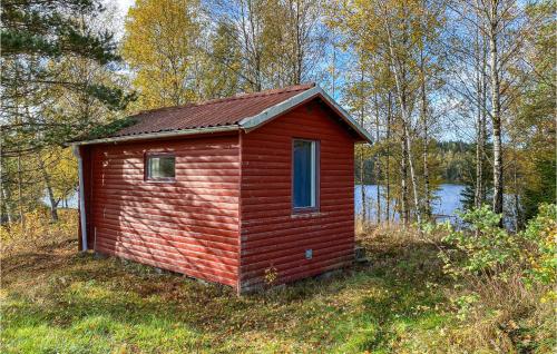 un petit bâtiment rouge dans l'herbe près d'une masse d'eau dans l'établissement Cozy Home In Ambjrnarp With Kitchen, à Ambjörnarp