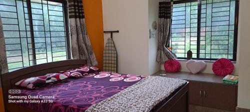 a bedroom with a purple bed and two windows at Shree Homestay in Manipala