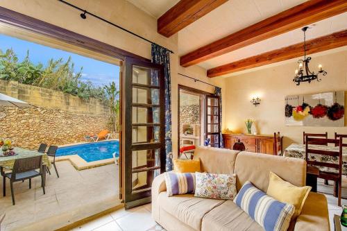 a living room with a couch and a sliding glass door at Razzett ta' Leli Holiday Home in Xagħra