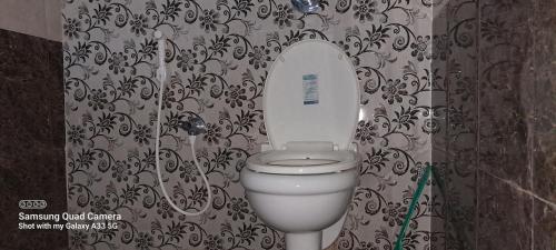 a bathroom with a toilet with a black and white wallpaper at Shree Homestay in Manipala
