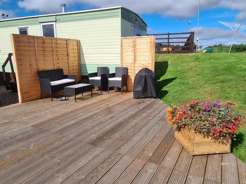 a deck with chairs and a table and flowers at Rowanlea Caravan in Stonehaven