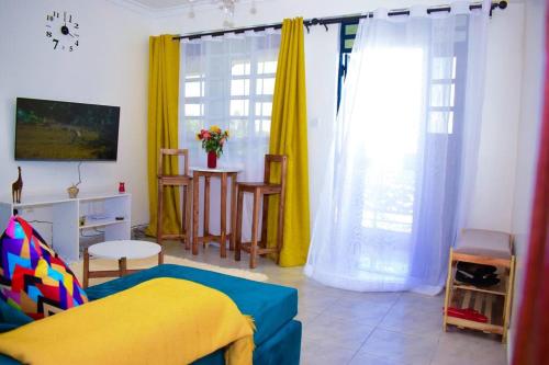 ein Wohnzimmer mit einem Bett und gelben Vorhängen in der Unterkunft Rorot 2 bdrm stay located Annex home away(bright) in Eldoret