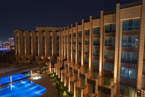 un edificio con piscina por la noche en Grand Millennium Al Seef Basra en Basora