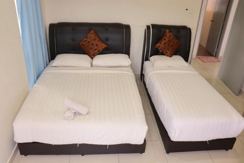 two beds in a room with white sheets at ATS Cameron Hotel & Apartments in Cameron Highlands