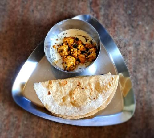 a plate with a bowl of food and a tortilla at Shree Homestay in Manipala