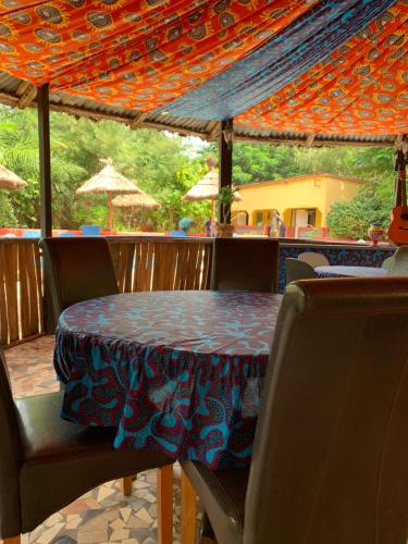 a table and chairs with a table and an umbrella at The Gunjur Project Lodge in Gunjur
