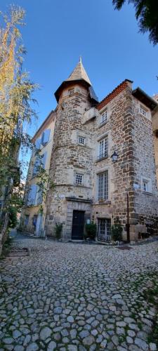 un gran edificio de piedra con una torre en una calle en Maison au Loup - Superbe ancien hotel particulier du XVIe siècle au cœur de la vieille ville du Puy, en Le Puy en Velay