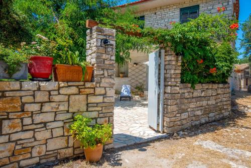 a brick wall with a door and some plants at Acacia APT by Aglaia V in Vlachopoulátika