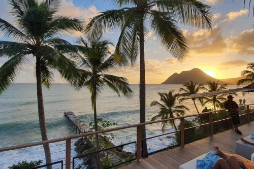 a view of the ocean from a resort with palm trees at Caraïbe Diamond Studio in Le Diamant