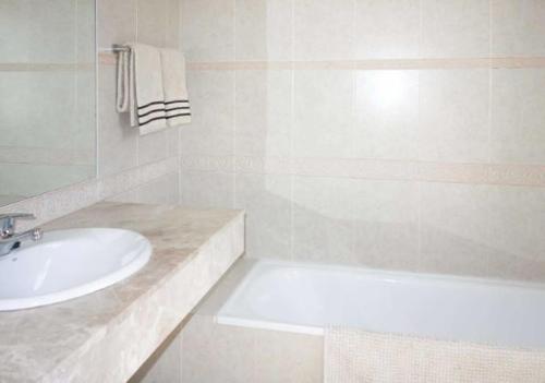 y baño blanco con lavabo y bañera. en Villa La Hubara, en Caleta de Fuste