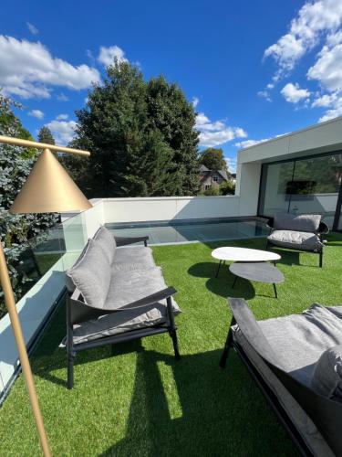 eine Terrasse mit Stühlen, einem Tisch und Gras in der Unterkunft Comme chez Lore - villa 2pers - piscine chauffée in Namur