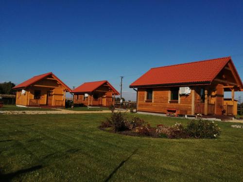 zwei Holzhütten mit roten Dächern auf einem Feld in der Unterkunft Bella Przystań in Zator