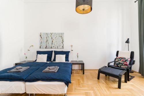 a bedroom with a blue bed and a chair at Black & white apartment Budapest in Budapest
